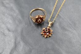 A 9ct gold garnet set cluster ring, the central round cut garnet in a six round cut garnet surround,