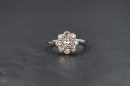 An 18ct white gold diamond set cluster ring, the central round brilliant cut diamond measuring