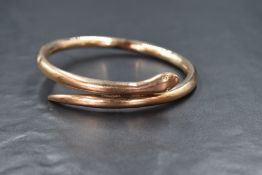 A 9ct rose gold snake/serpent bangle of plain form having embossed eyes and open mouth, hallmarks