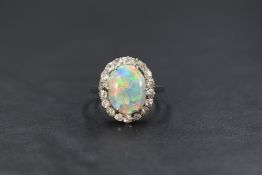 A white metal opal and diamond cluster ring, the central opal measuring approximately 11.9mm x 9.2mm