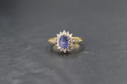 An 18ct gold sapphire and diamond set cluster ring, the central oval cut sapphire measuring