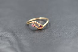 A 9ct gold ring having two small ruby chip terminals on crossover shoulders to 9ct gold loop, size L