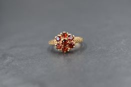 A 9ct gold garnet set cluster ring, the central round cut garnet in six round cut garnet surround,