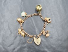 A 9ct gold curb link charm bracelet, having a heart padlock marked 9ct and five gold charms