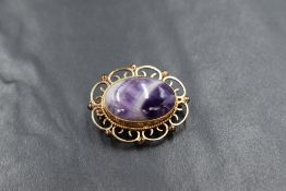 A gold presumed 9ct amethyst set brooch, the bezel set oval cabochon in a decorative pierced