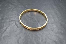 A 15ct gold bangle, having engine turned decoration, marked 625, 7.5cm internal diameter, 12.5g.