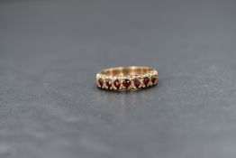 A 9ct gold garnet set half eternity ring, the seven round cut garnets in claw settings, marked