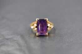A 9ct gold amethyst and diamond set ring, the central emerald cut amethyst measuring approximately