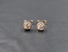 A pair of white metal diamond solitaire stud earrings, each brilliant cut diamond being