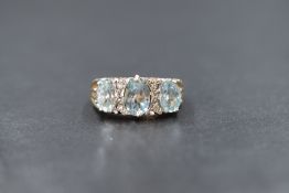 A 9ct gold aquamarine and diamond trilogy ring, the three graduated oval cut aquamarines measuring