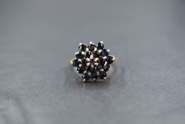 A 9ct gold sapphire triple cluster ring having a raised claw set mount on a 9ct gold loop, size