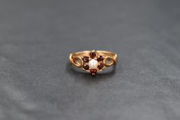 A 9ct gold pearl and garnet set cluster ring, the central cultured split pearl in a six round cut