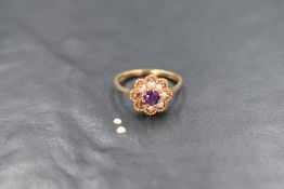 A 9ct gold amethyst and seed pearl set cluster ring, the central round cut amethyst in an eight