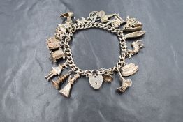 A silver curb link charm bracelet, having a silver heart padlock and seventeen silver and white