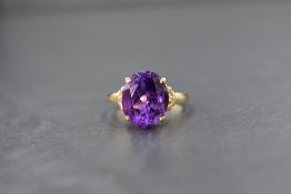 A 14ct gold amethyst and diamond set dress ring, the central oval cut amethyst measuring