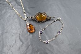 A silver amber set brooch, the amber oval cabochon in a bezel setting with branch and leaf