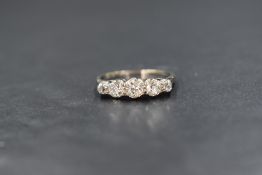 A platinum and gold diamond set five stone ring, the graduated old cut diamonds measuring
