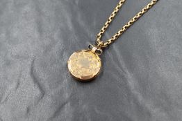 A yellow metal presumed gold locket, of circular form having a vacant shield and engraved scroll
