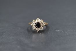 A 9ct gold sapphire and diamond set cluster ring, the round cut sapphire in an eight illusion set