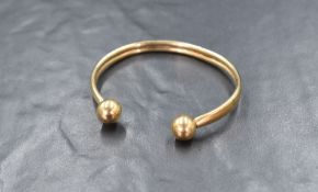 A 9ct gold torque bracelet, the rounded cuff bracelet having a ball to each end, marked 375, 6cm
