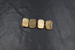 A pair of 9ct gold cufflinks having engraved front panels with chain connectors to back panels,
