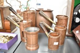 A 19th century copper jug having shaped handle, h20cm, sold together with a set of 5 copper ale