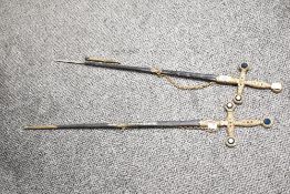 A pair of decorative ceromorial swords having metal handles with purple, red and green costume