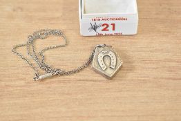 A Victorian silver locket of pentagon form bearing horse shoe motif to front, on a white metal
