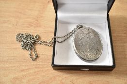 A large oval silver locket having floral decoration and brushed finish, on a 22