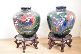 A pair of Decoro pottery vases of lobed form, decorated with floral patterns on a deep green ground,