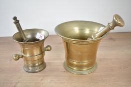 A solid brass pestle and mortar, h11.5cm, sold together with a similar pestle, (2)