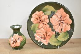 A Moorcroft pottery 'Coral Hibiscus' pattern plate, decorated with floral designs on a olive green