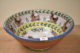 A large terracotta bowl hand coloured with roosters and floral motifs, w47cm Condition report: