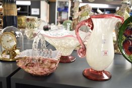 A 20th century white opalina and red glass pitcher, having shaped handle and spout, raised on a