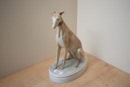 A Hungarian porcelain Greyhound study, sitting on oval base, markings to underside.