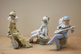 A group of three Nao by Lladro porcelain clown musician figurines in white, yellow and blue