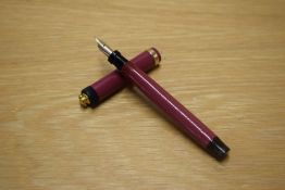 A Parker Duofold Lucky Curve button fill fountain pen in Magenta with a wide cap band on a ringtop