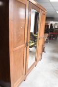 An early 20th Century mahogany triple wardrobe having central mirror door, width approx. 199cm