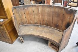 A rustic bench, of curved form, possibly constructed from cut down beer vat or similar, width