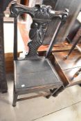 A period oak dining chair having solid seat and figural decoration to back