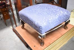 An early 20th century footstool having blue upholstery and cabriole legs