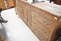 A rustic part scumbled pine sideboard having central cupboard flanked by two banks of three drawers,