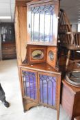 An Edwardian full height corner corner display having gothic style glazing and central mirror