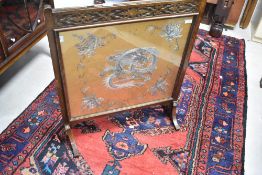 An early 20th Century oak firescreen having embroidered silk panel , dragon decoration, width