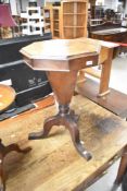 A Victorian walnut sewing table having octagonal top on triple legged base, diameter approx. 43cm