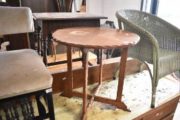 An Arts and Crafts style golden oak occasional table having circular adzed top and X frame, diameter