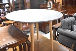 A modern circular dining table in the vintage style having grey powder coated top on beech splay
