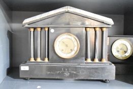 A 19th century black slate 8-day mantel clock having Arabic chapter ring, flanked by a trio of