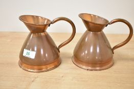 A pair of copper measuring jugs having shaped handle and spout, h12.5cm