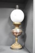An early 20th century brass oil lamp having circular white glass shade and clear glass chimney,